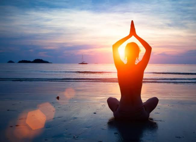 Exercício de yoga ao ar livre, na praia